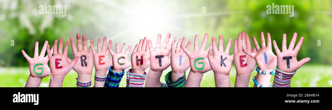Children Hands Building Word Gerechtigkeit Means Justice, Grass Meadow Stock Photo