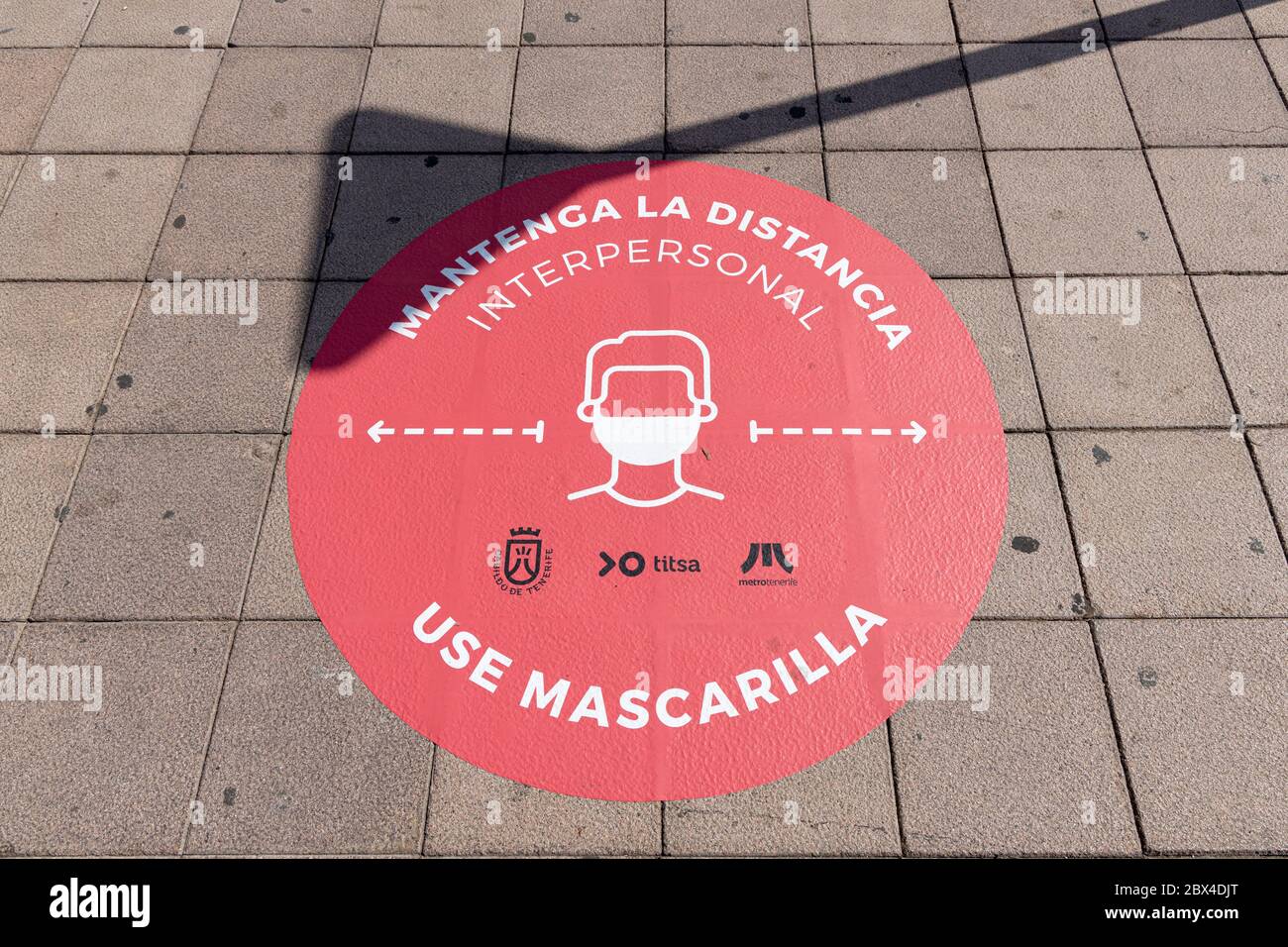 Round signs on the pavement advising to maintain distance and wear masks on public transport at Los Cristianos bus station during phase two de-escalat Stock Photo