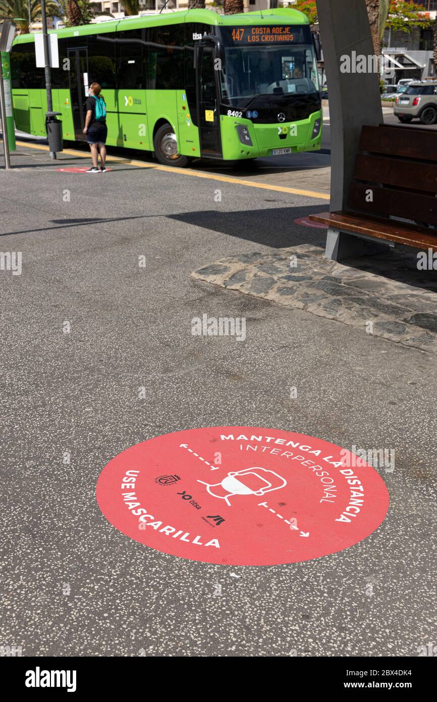 Round signs on the pavement advising to maintain distance and wear masks on public transport at Los Cristianos bus station during phase two de-escalat Stock Photo