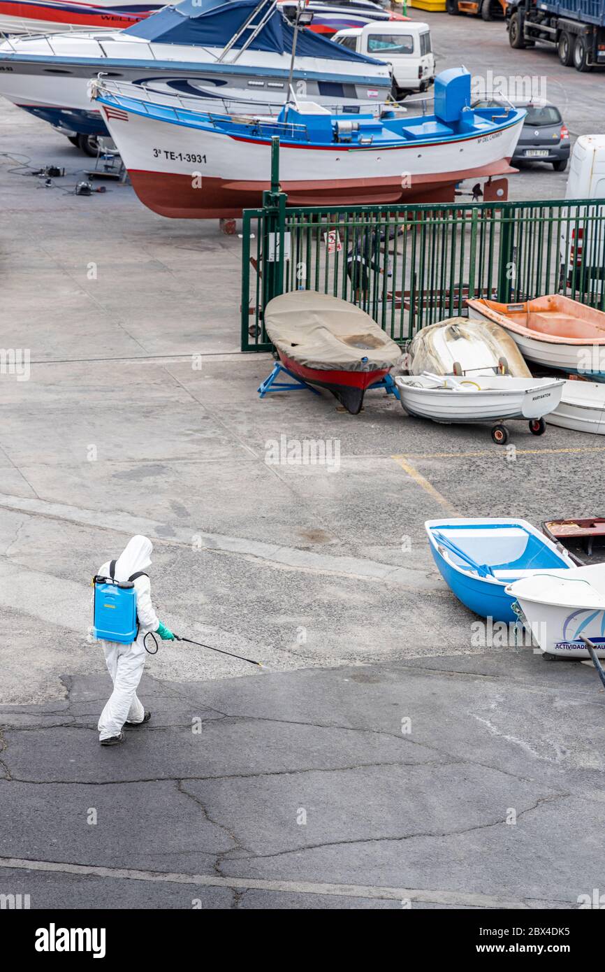 Man disenfects the tarmac around the port and quays , dressed in a protective suit and wearing a mask, during phase two of de-escalation from Covid 19 Stock Photo