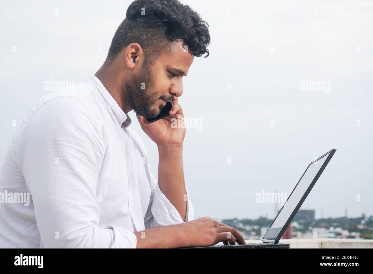 young man using laptop and smart phone together Stock Photo