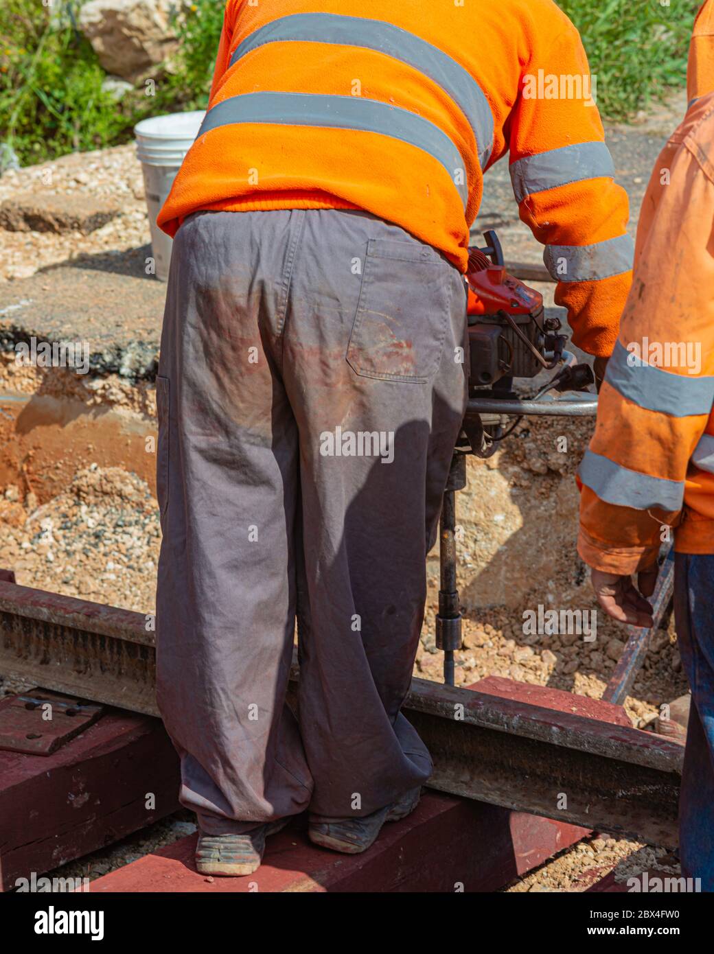 Railway workers bolting track rail. Detail worker with Light portable