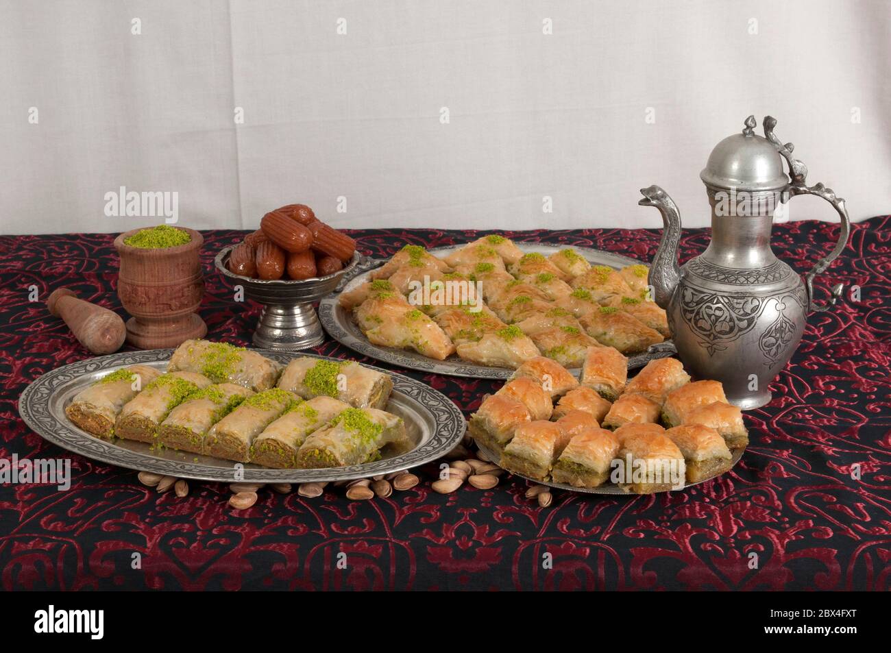 Traditional Turkish desserts on a table. Baklava and tulumba dessert. Desserts made from pistachio, walnut, dough and sugar sorbet. Stock Photo