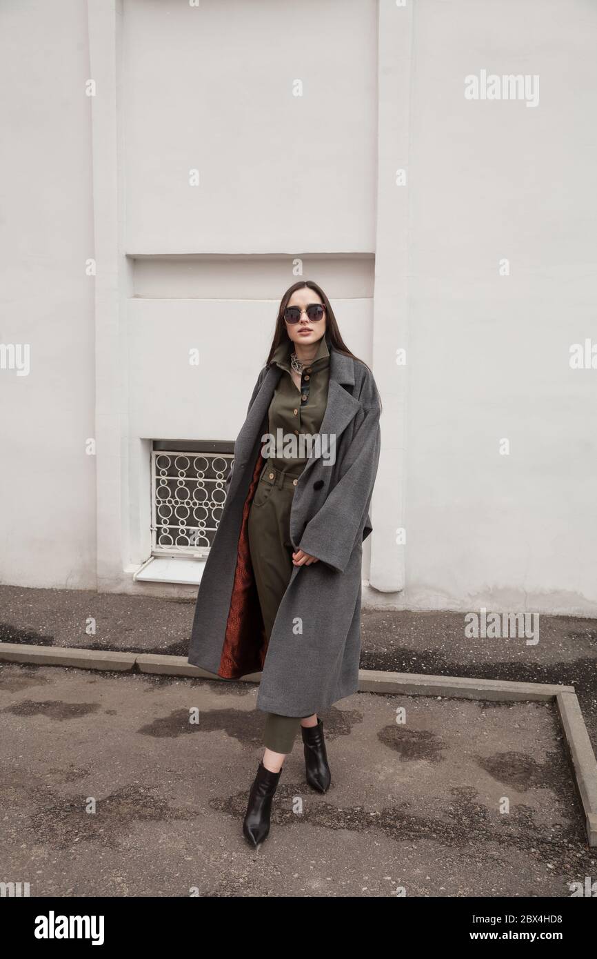 rban city, wearing gray coat and green suit, fashion look, alone waiting for her boyfriend outdoors. Low angle view of fashionable model itrendy Stock Photo