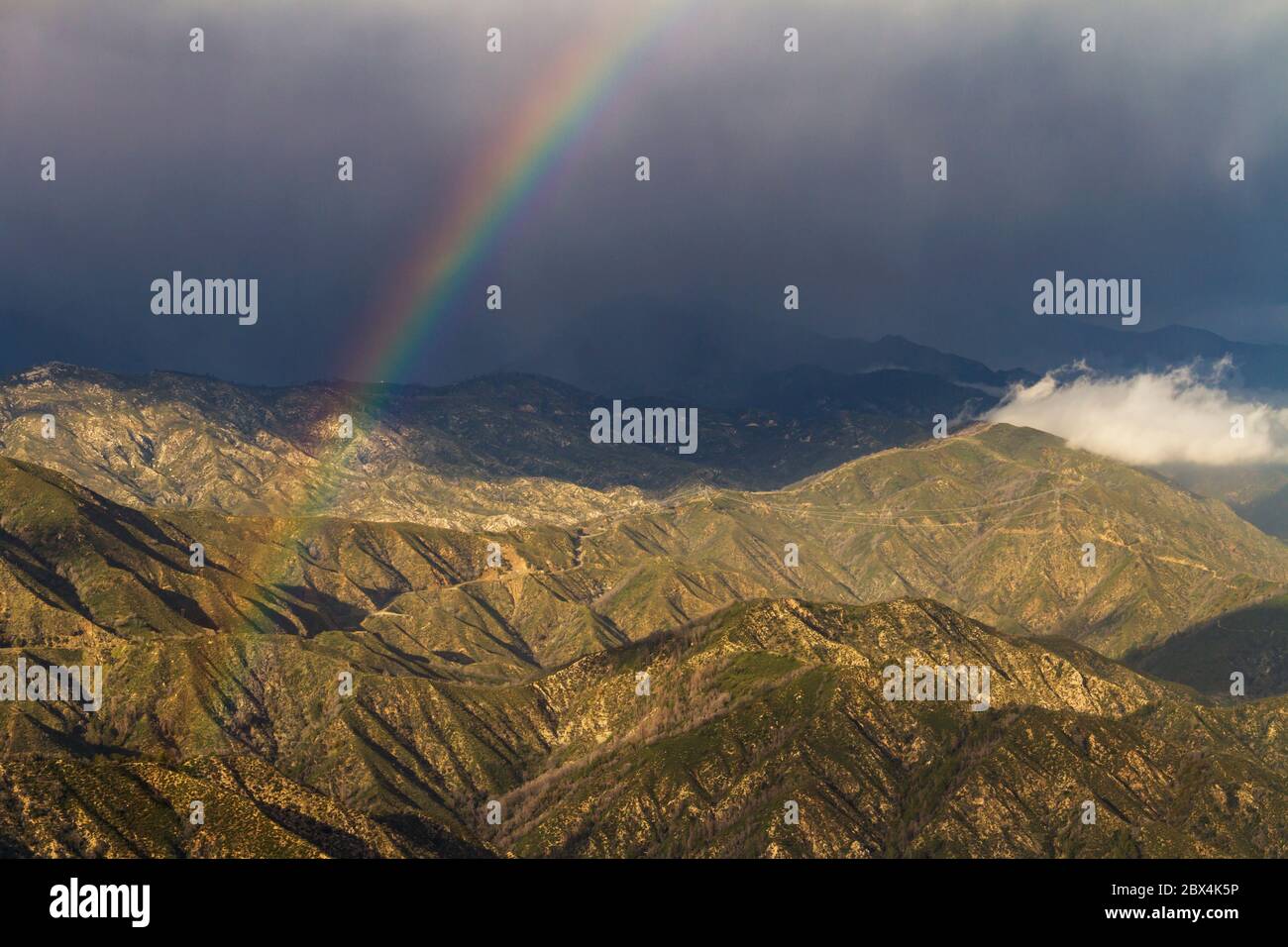 A rainbow cuts through the clouds in the San Gabriel Mountains of Southern California Stock Photo