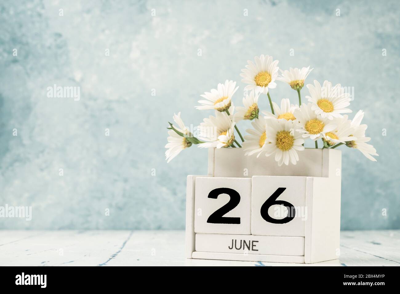 White cube calendar for june decorated with daisy flowers over blue ...