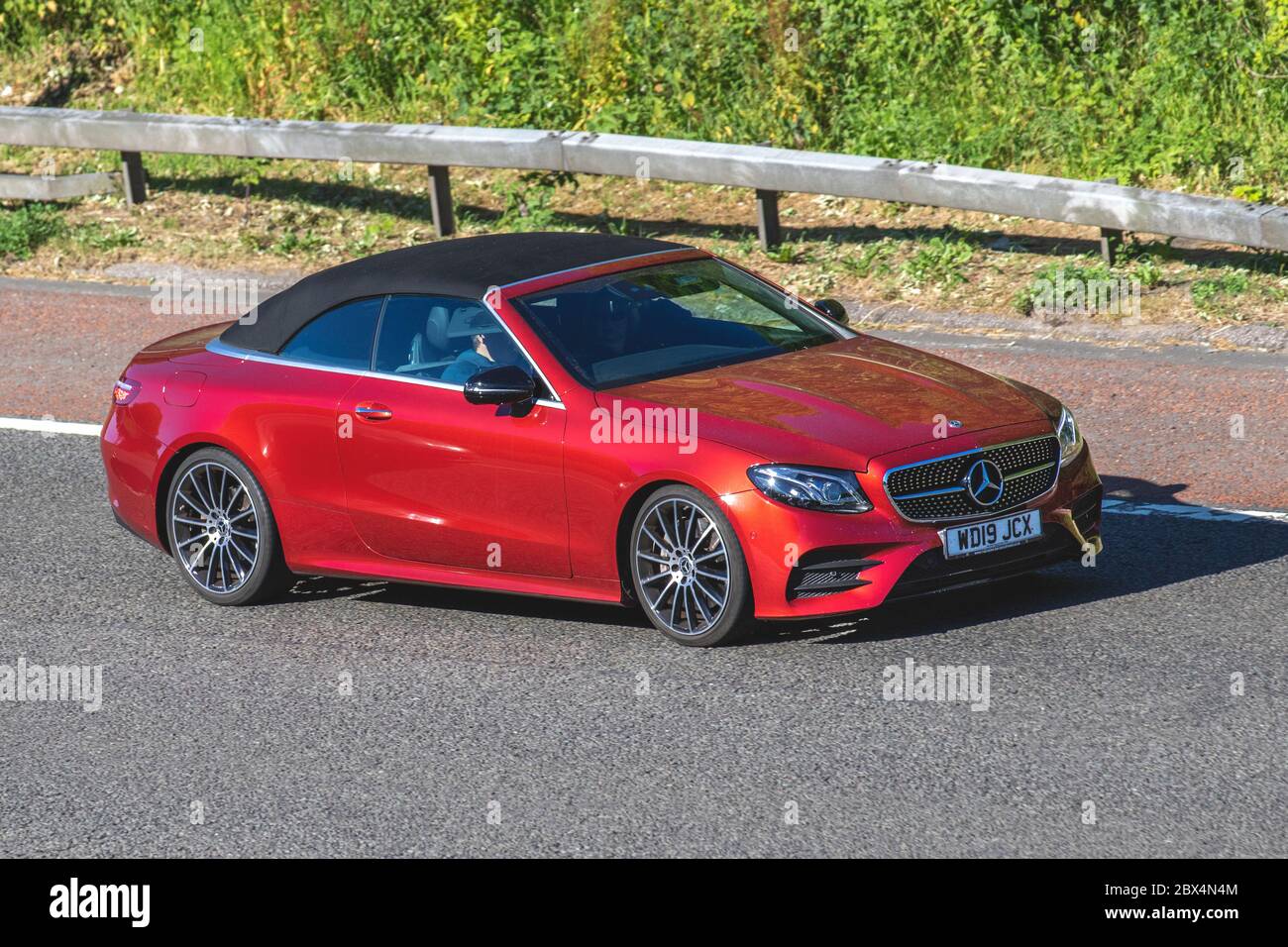 2019 red Mercedes-Benz E 300 AMG Line Auto; Vehicular traffic moving vehicles, convertible, convertibles, soft-top, open topped, roadster, cabriolets, drop-topscars driving vehicle on UK roads, motors, motoring traffic on the M61 motorway. Stock Photo