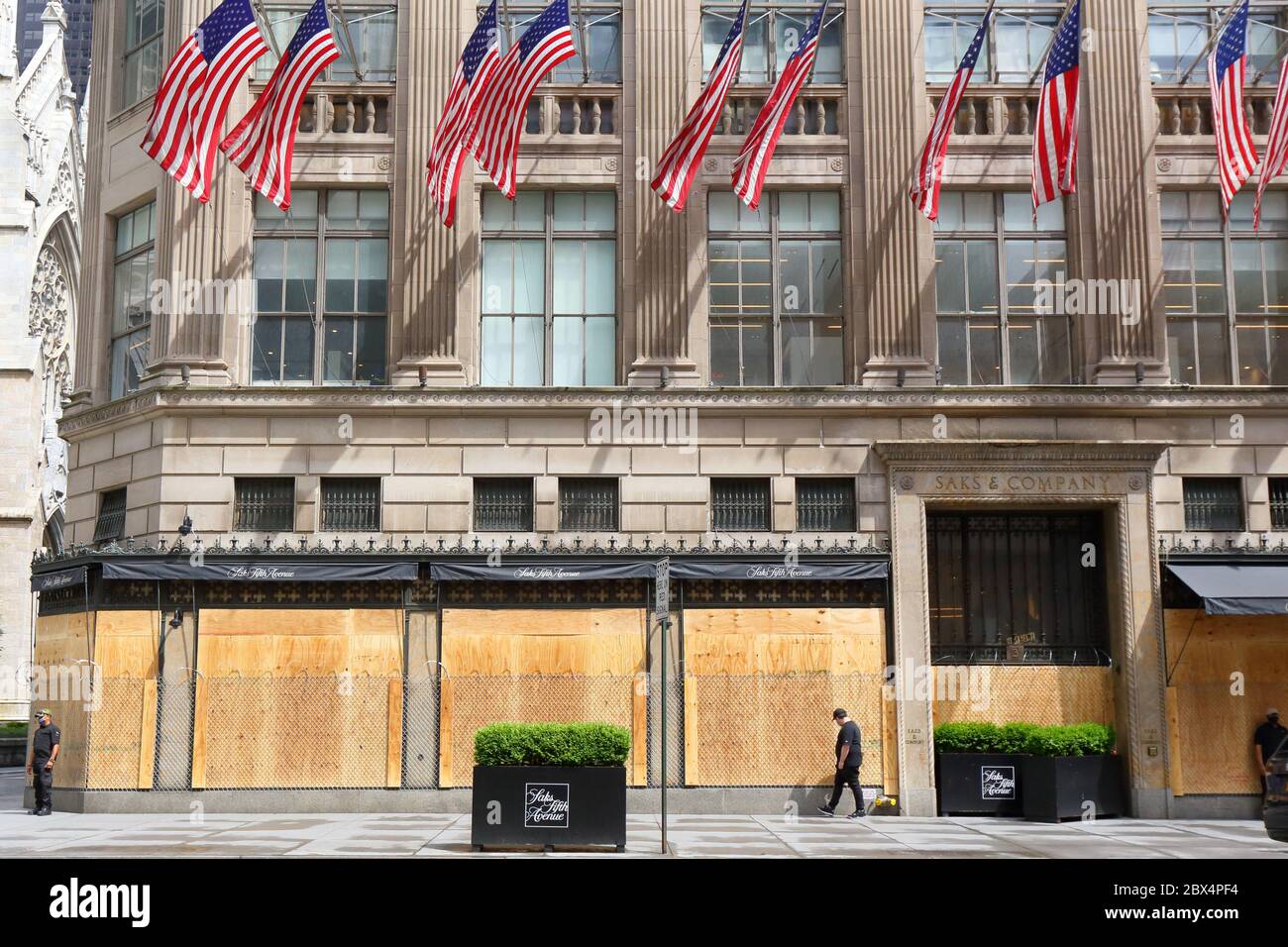 New York, NY. 3rd June 2020. The flagship Saks Fifth Avenue department store with boarded up windows, barbed wire, and American flags in response to a recent spate of large scale, organized burglaries/looting in various parts of the city. The barbed wire and private security appears to send an almost dystopian, and tone deaf message to the citizens of New York that all hope is lost.  On the flip side, it is an immensely Instagrammable photo op. The department store has been closed during the COVID-19 coronavirus pandemic. Stock Photo