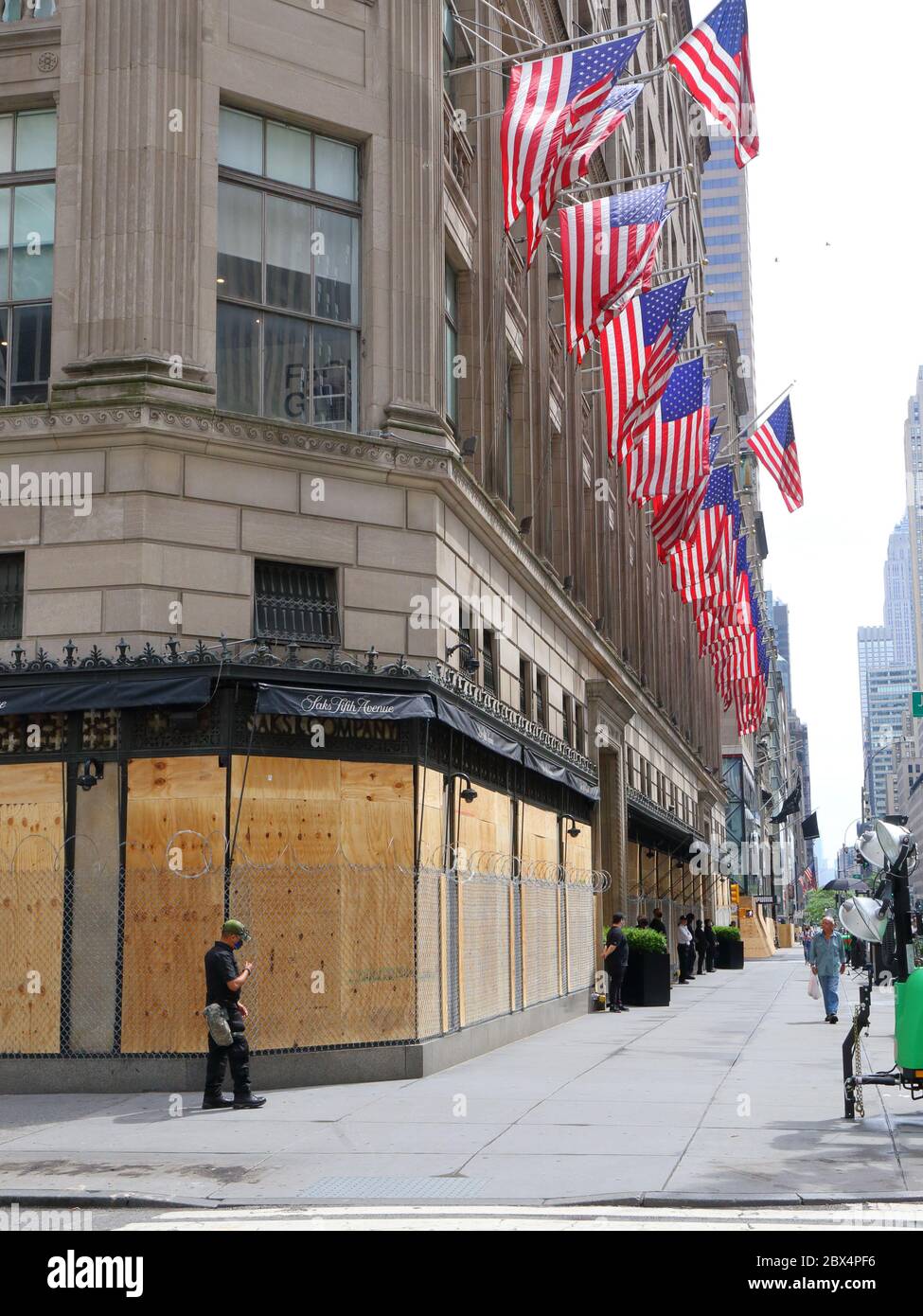 New York, NY. 3rd June 2020. The flagship Saks Fifth Avenue department store with boarded up windows, barbed wire, and American flags in response to a recent spate of large scale, organized burglaries/looting in various parts of the city. The barbed wire and private security appears to send an almost dystopian, and tone deaf message to the citizens of New York that all hope is lost.  On the flip side, it is an immensely Instagrammable photo op. The department store has been closed during the COVID-19 coronavirus crisis. Stock Photo