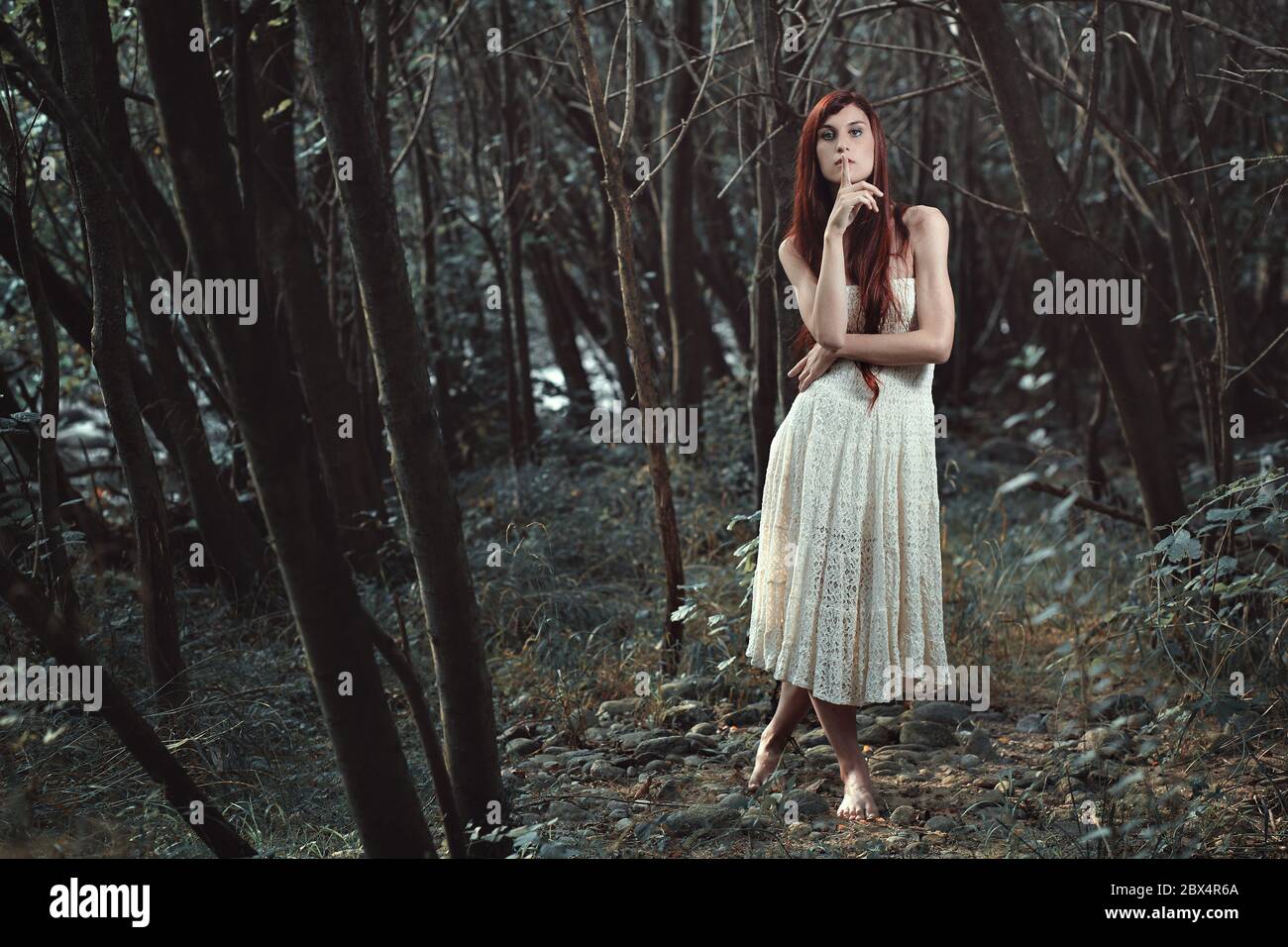 Silence gesture from red hair woman. Surreal forest Stock Photo