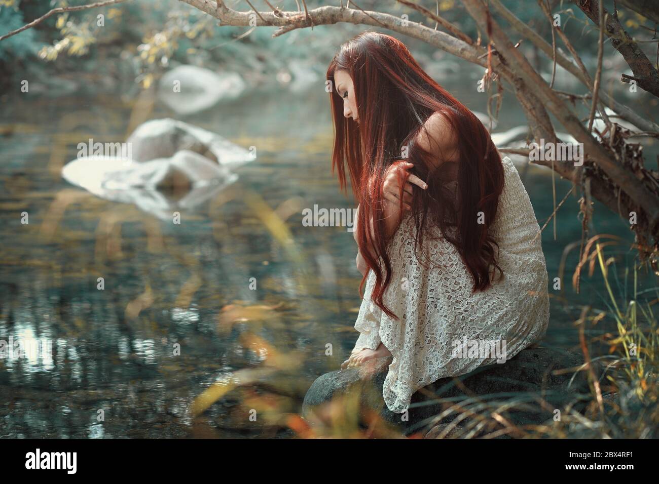 Thoughtful red hair woman looking at stream waters. Autumn colors Stock Photo