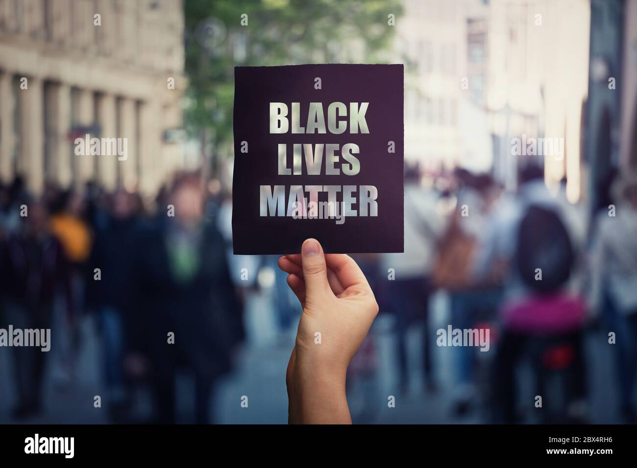 Black Lives Matter, street demonstration. Human hand holds a dark protest banner, against injustice. USA black people rights, social problems concept, Stock Photo