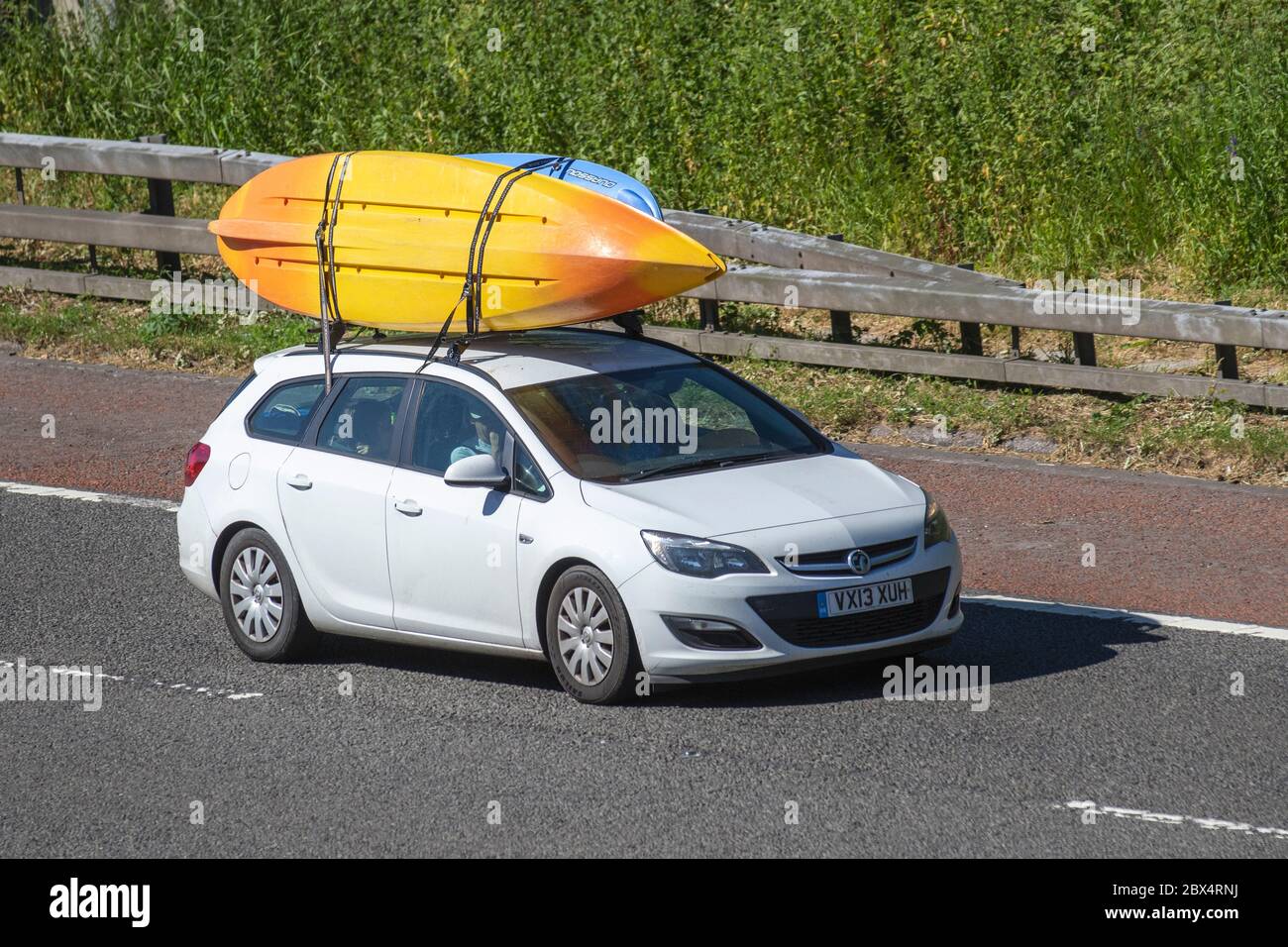 2013 white Vauxhall Astra 1.3 CDTi ecoFLEX Exclusiv 5dr. 5 door Manual Diesel Hatchback; carrying two canoes; Vehicular traffic moving vehicles, cars driving vehicle on UK roads, motors, motoring on the M6 motorway highway Stock Photo