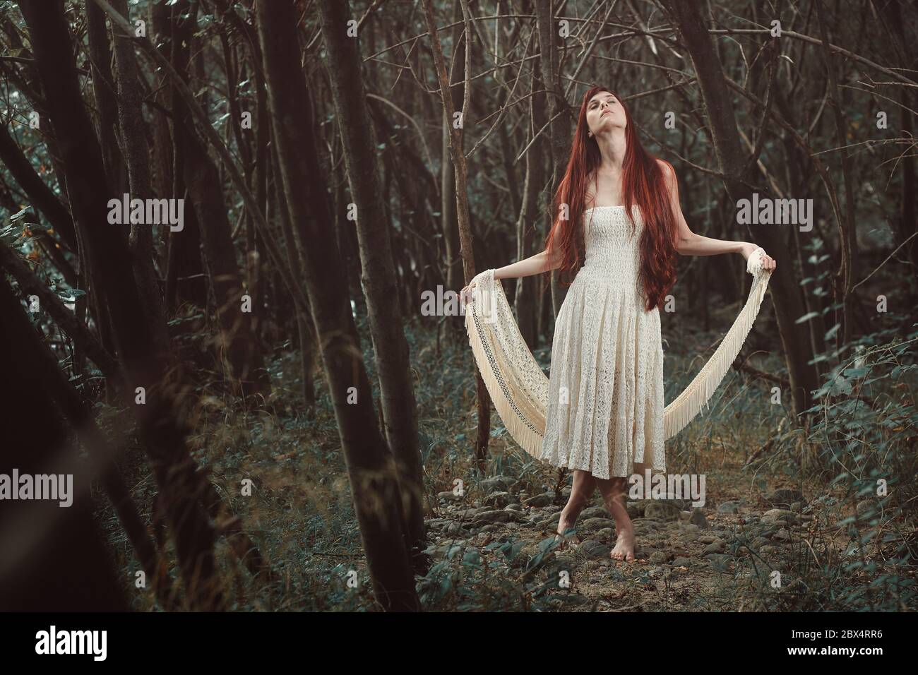 Beautiful red hair woman dancing in secret forest. Surreal and fantasy Stock Photo