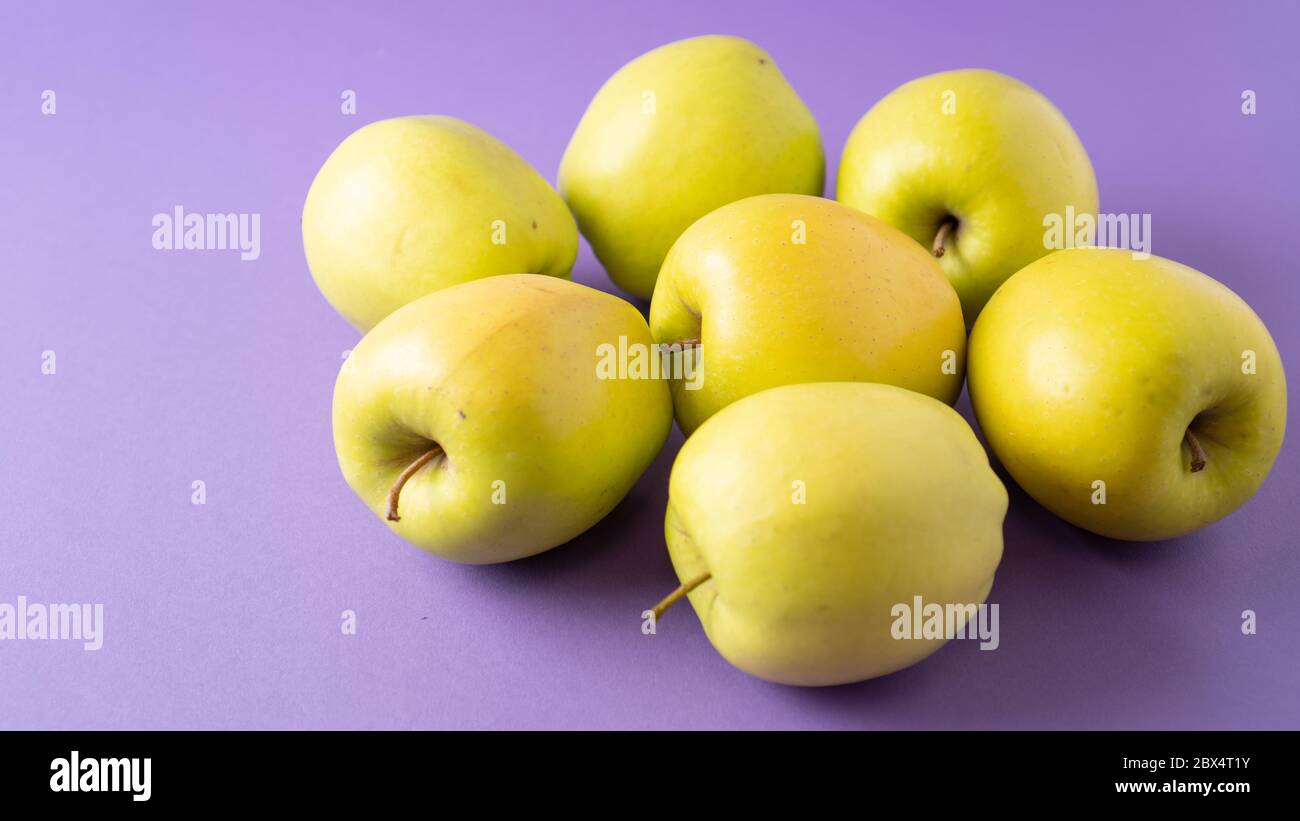 Yellow apples on violet background. Concept of healthy food for teeth. Bright juicy and ripe apples. Wallpaper Stock Photo