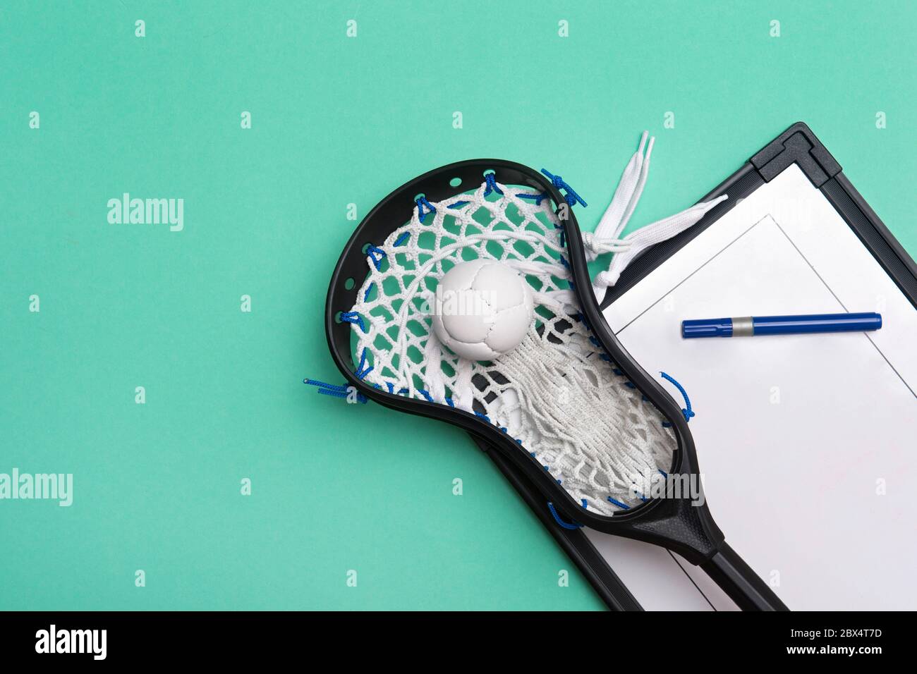 Lacrosse stick, ball and tactical board with marker on green background