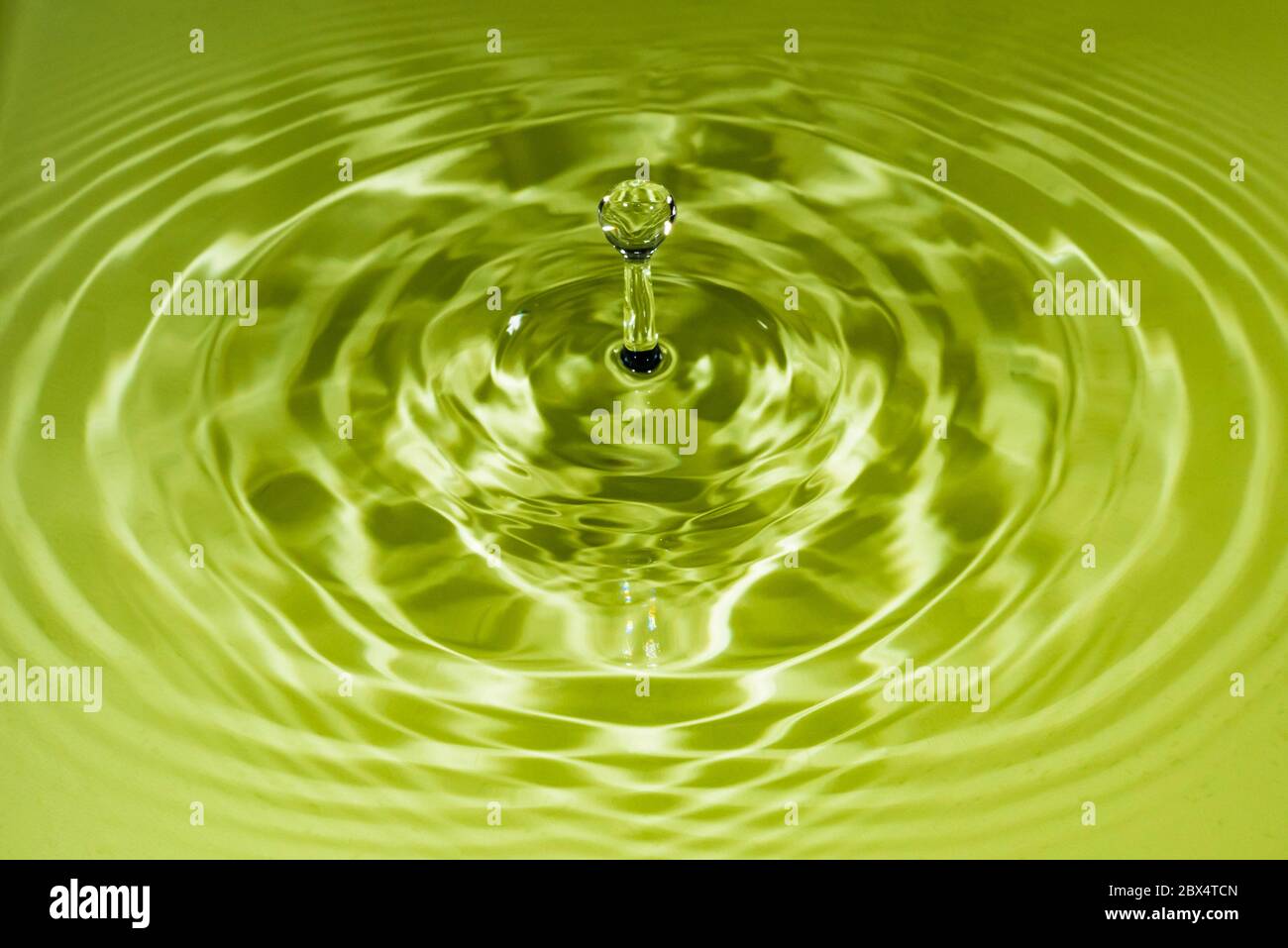 Studio close-up of a high-speed water droplet against a green backdrop Stock Photo