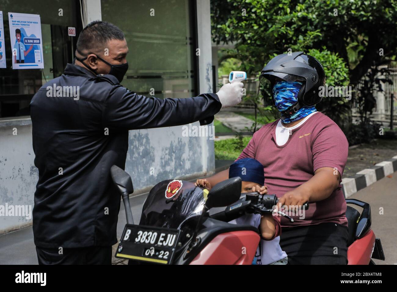 A Security Guard Checks The Body Temperature Of A