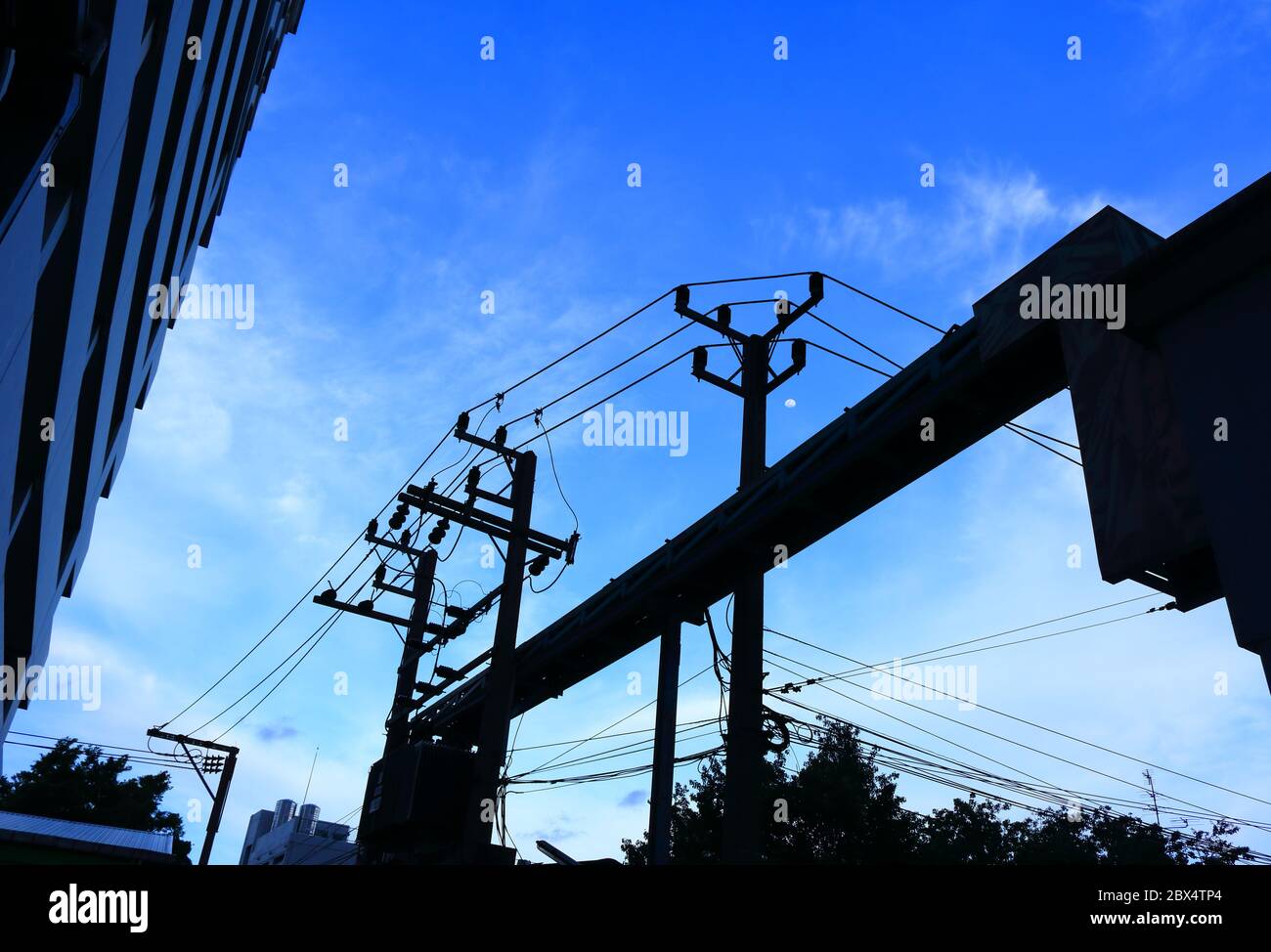 Silhouette image of electric pole with power lines and cable tray