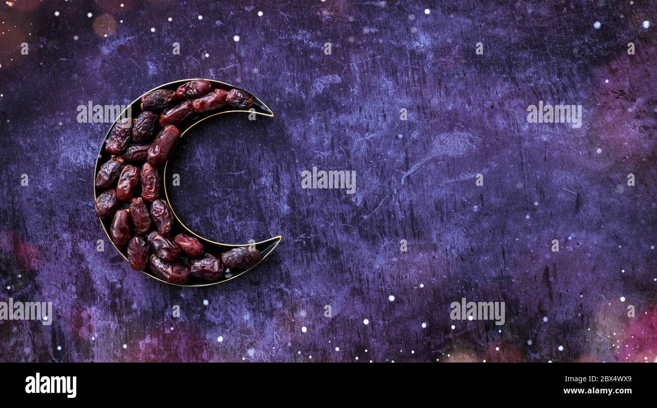 Dates in a moon shaped plate Islamic Iftar and Eid Al Adha concept background, colorful dates image decorated with  shape of crescent moon Stock Photo