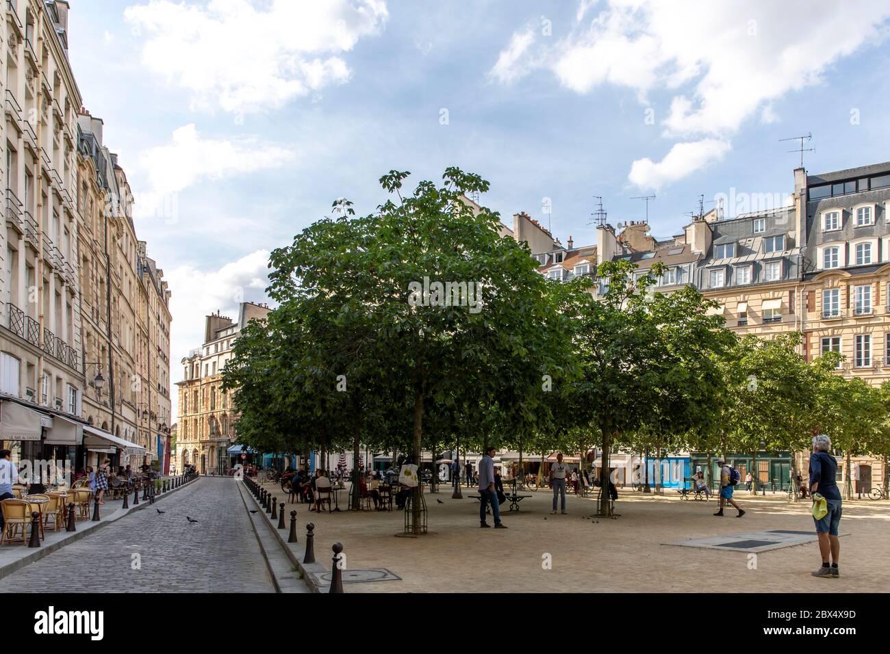 Paris, France - June 3, 2020: People playing petanque. In the background people eat again on the terrace of the restaurants after the end of lockdown. Stock Photo