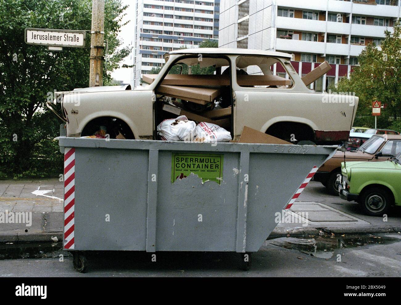 Berlin-Mitte / GDR / 1990 A Trabi, symbol of GDR prosperity, is disposed of, near Leipziger Strasse, a symbol for the end of the GDR // Muell / Abfall / Einigung / Wende / Wirtschaft / *** Local Caption *** East Germany / CommunismThe car Trabi-Trabant was the standard car in communist Germany, a sign for moderate wealth. After the unification those cars were only junk, like big parts of the whole economy.the communist symbol in a junk carbage container [automated translation] Stock Photo