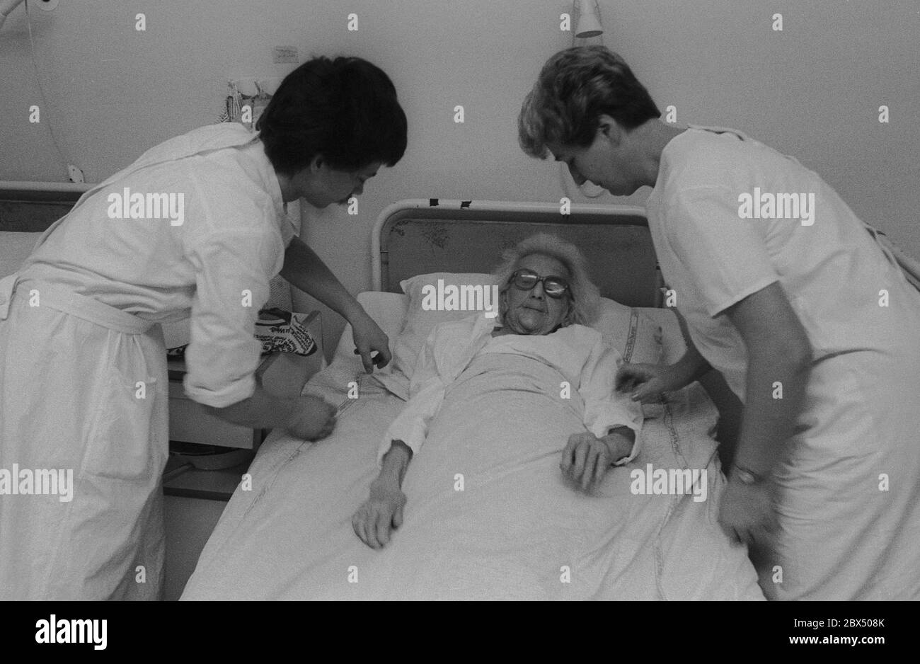 Berlin / Prenzlauer Berg / Health / GDR / 3 / 1990 Old woman in Prenzlauer Berg hospital, ward for chronically ill patients. There are 8 beds in the room. Nurses. // Seniors / Care / Old People / *** Local Caption *** East Germany / Communist Germany / Health Hospital in Prenzlauer Berg, Quarter of East Berlin. [automated translation] Stock Photo