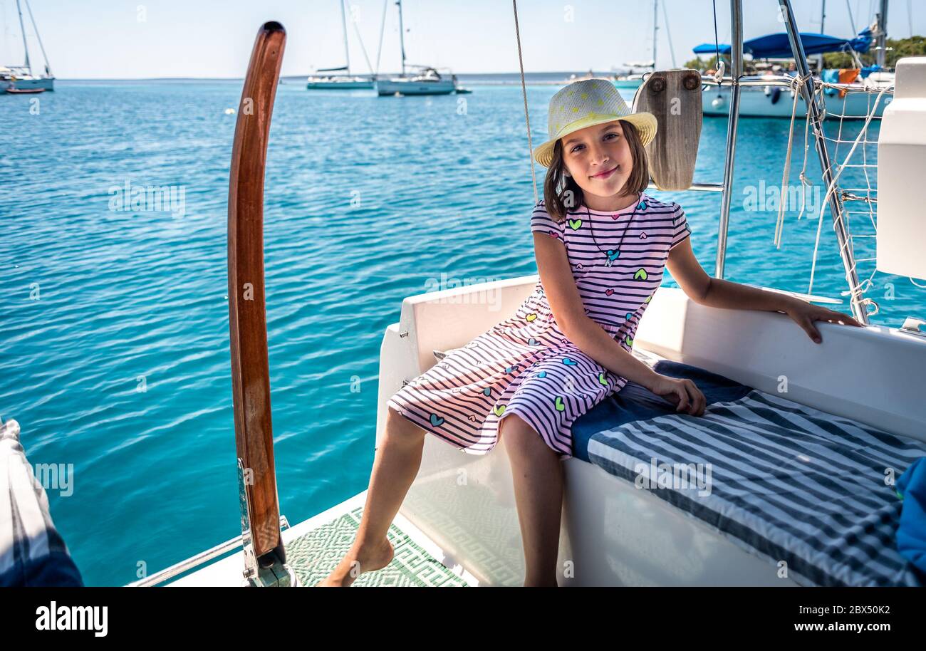 Child on sailing boat yacht summer vacation adventure. Happy girl is enjoying a summer trip on a sailboat moored in an amazing bay in the Adriatic sea Stock Photo