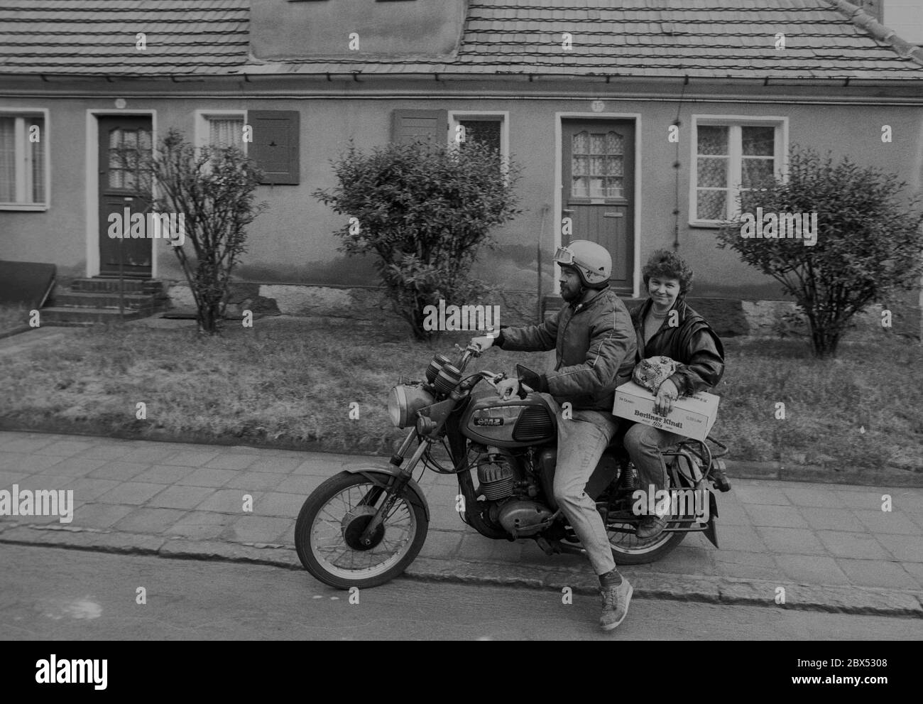 Saxony-Anhalt / GDR state / 1990 GDR couple on motorcycle MZ in the workers' housing estate Piesteritz near Wittenberg. It belonged to the former nitrogen works, built in 1915 for ammunition production. It is a nice closed residential area, with gardens behind the house and traffic-calmed inner courtyards. It was renovated in 2000. (see new photos) // GDR citizens / couple / people / [automated translation] Stock Photo