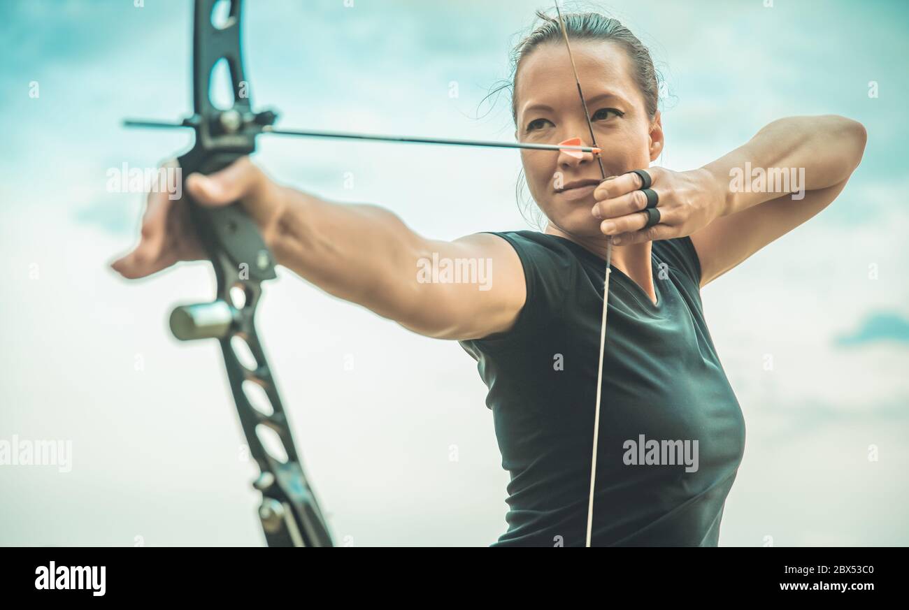 archery, young woman with an arrow in a bow focused on hitting a target