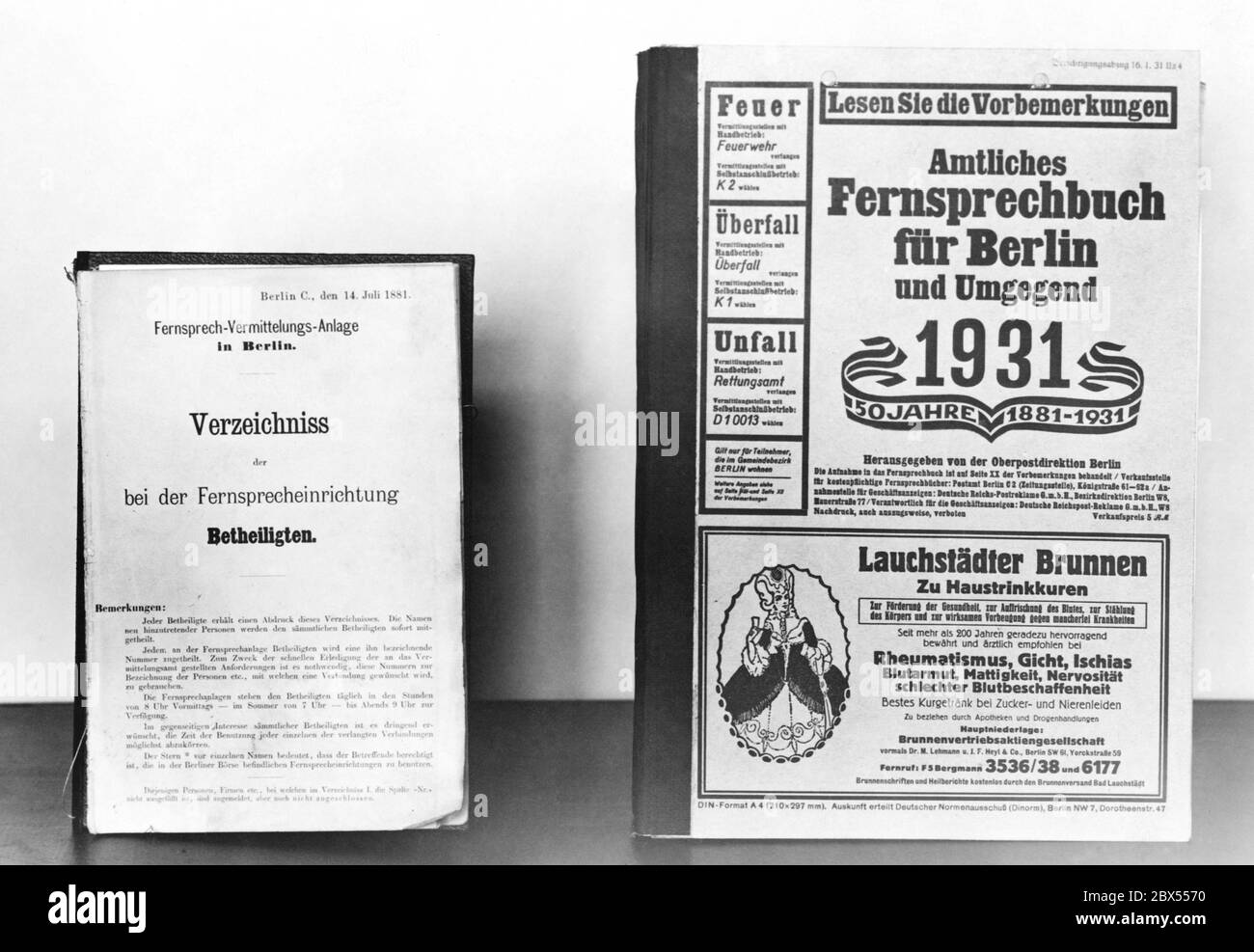 On the left, the first telephone book of Berlin with the name: 'Verzeichniss der bei der Fernsprecheinrichtung Beteiligten.' ('Directory of those connected to the telephone system.') With rules for telephone calls. It had only 17 pages. On the right, an 'Amtliches Fernsprechbuch fuer Berlin und Umgegend' ('Public telephone directory for Berlin and the surrounding area') from 1931 with an advertisement for the product 'Lauchstaedter Brunnen'. Photo from the 1930s. Stock Photo