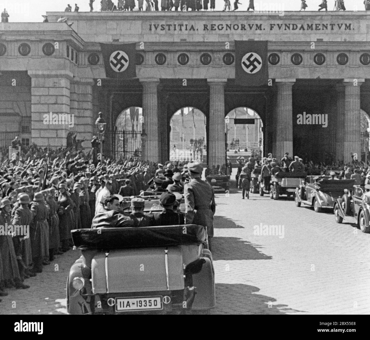Adolf Hitler enters the Heldenplatz in Vienna with his convoy through the Outer Castle Gate. There he announces the annexation of Austria to the German Reich. On the gate is written: Iustitia Regnorum Fundamentum (Justice is the basis of the rule / kingdom). Stock Photo