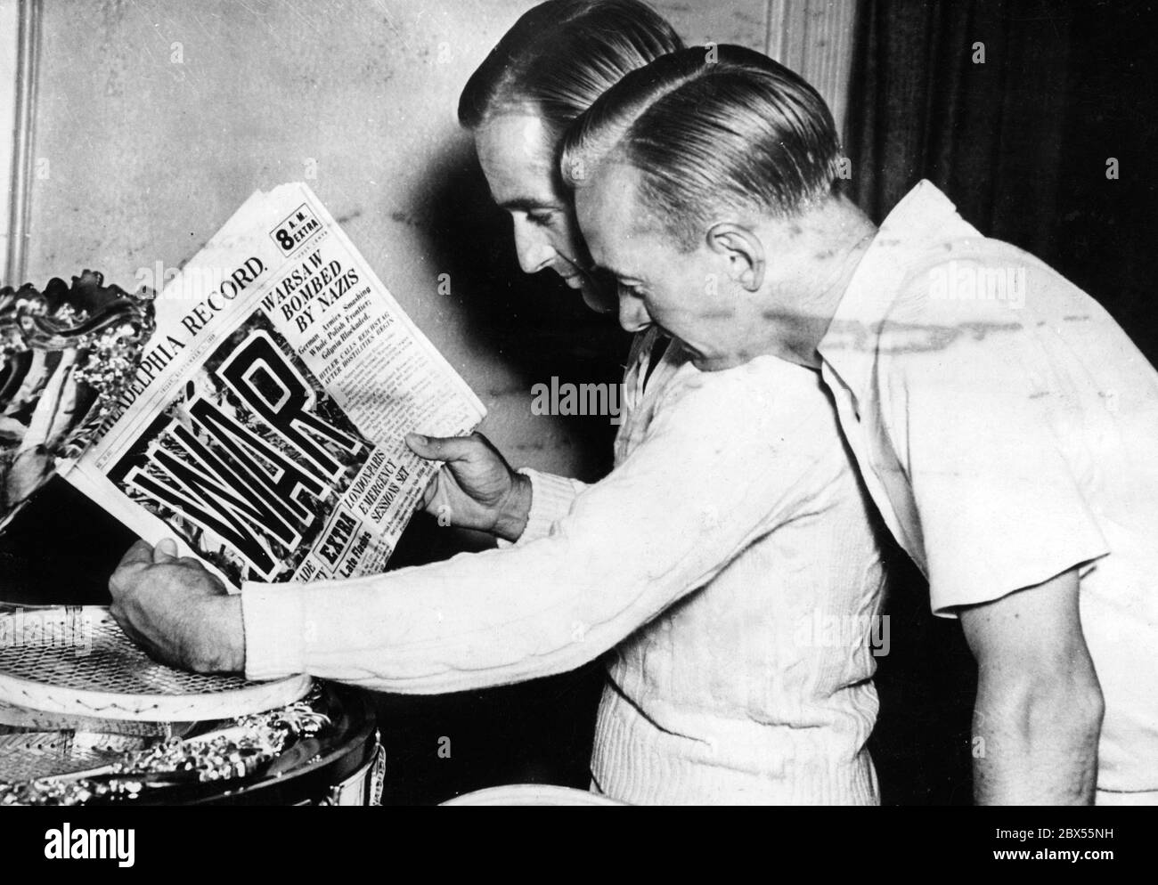 Adrian Quist (left), tennis player in the Australian Davis Cup team, and Harry Hopman (right), captain of the team, reading the headlines about the German invasion of Poland and the beginning of the war in an American newspaper, the 'Philadelphia Record'. Both belong to the Australian Army Reserve and can expect to be drafted if Great Britain enters the war. Stock Photo