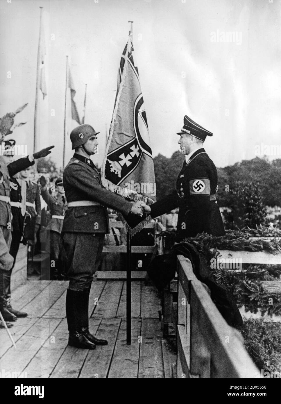 SS-Sturmbannfuehrer Hans-Friedemann Goetze (left) of the SS-Heimwehr receives a new troop flag from the Gauleiter of the NSDAP in Danzig, Albert Forster (right). Stock Photo