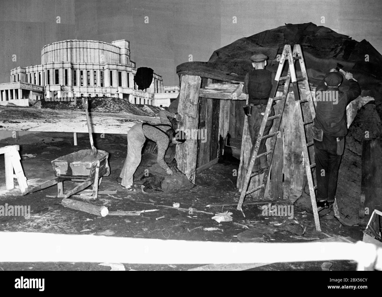 Preparations for the exhibition 'The Soviet Paradise' in Berlin's Lustgarten: Workers build a dugout, next to it is a picture of an opera in Minsk, which is supposed to symbolize the contrasts in a propagandistic way. Stock Photo