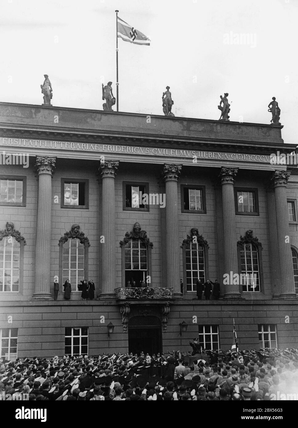 The flag of the National Socialist German Students' Union is raised for the first time on the main building of Berlin University. Below the balcony at the lectern there is an SS man. Stock Photo