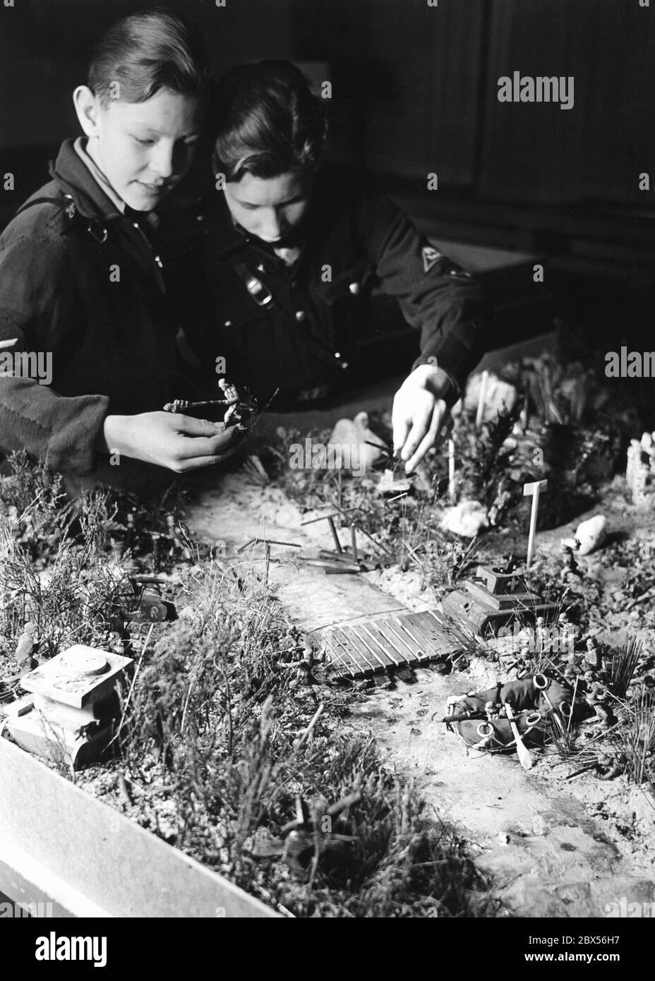Two students of the Westendschule Eberswalde at their sandbox work for the exhibition 'Ran an den Sandkasten' of the National Socialist Teachers' Association (Reich Administration, Liaison Office Berlin). It depicts a river crossing with raft bags and makeshift bridges. Besides that, toy soldiers and toy tanks. Stock Photo
