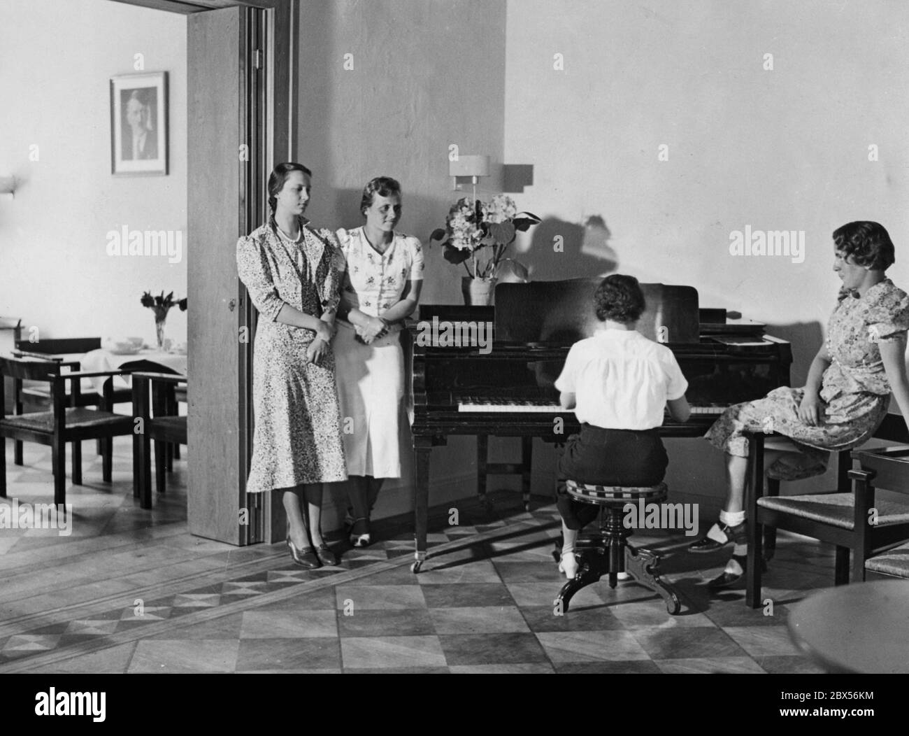 Students of the Labor Association of National Socialist Female Students (Arbeitsgemeinschaft nationalsozialistischer Studentinnen)  in the music room of their new dormitory in Berlin C, Oranienburgerstrasse 19. On the left wall is a portrait of Adolf Hitler. Stock Photo