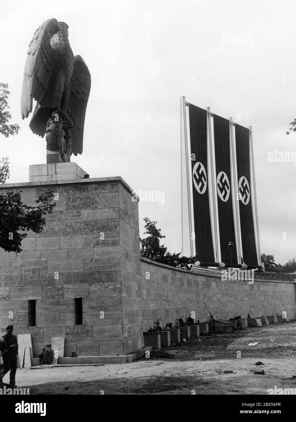 During the construction work in the Luitpoldarena a flag rehearsal is carried out with three swastika flags for the Reich Party Congress. On the left the sovereign symbols: Imperial Eagle with swastika. Stock Photo