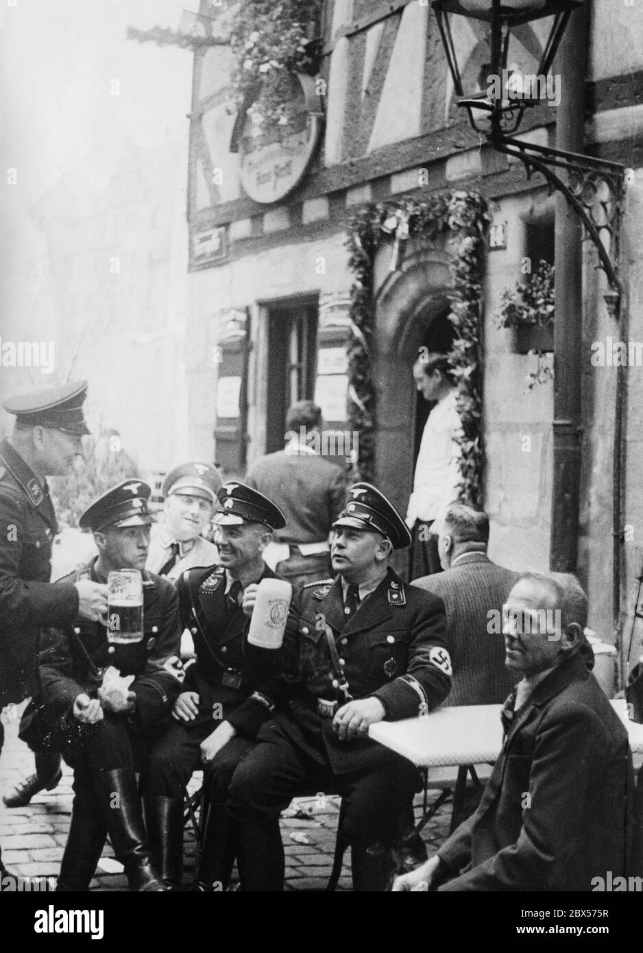 Many participants of the Reich Party Congress in Nuremberg enjoy Bavarian beer during their stay, like here in front of a tavern during a break. Stock Photo