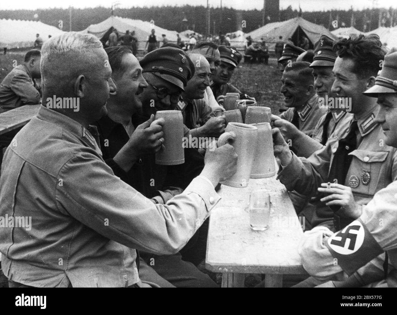 In the camp Harnisch Schlag of political leaders from Berlin, party officials are cheerfully toasting with beer mugs. Stock Photo