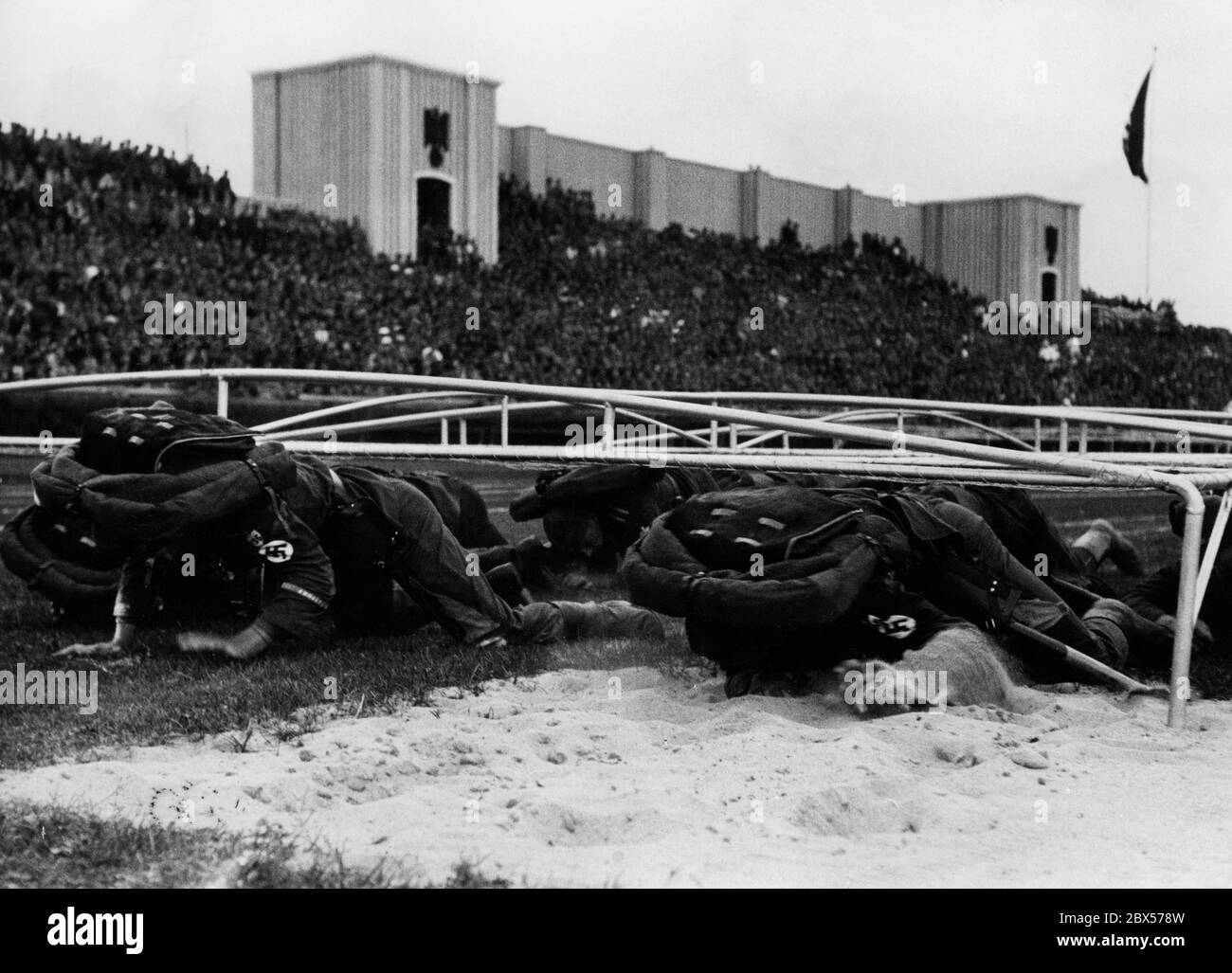 SA members crawl with their knapsacks on their backs. This competition takes place at the NSDAP Reich Party Congress in Nuremberg. Stock Photo