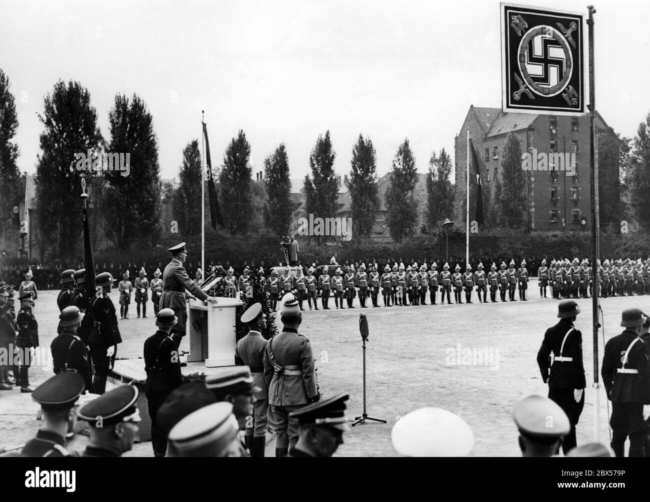 Adolf Hitler gives a speech on the Deutschherrenwiese to the 3000 police officers who appeared in front of him for the presentation of 23 flags. In the background is a cameraman. Stock Photo