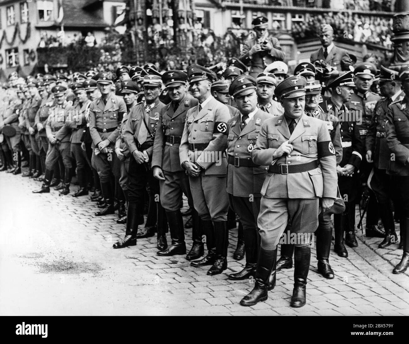 From right to left: Martin Bormann, Robert Ley, Wilhelm Frick, Hans Frank, Franz Ritter von Epp and Joseph Goebbels watch the parade of Nazi formations on Nuremberg's Main Market Square. 3rd row far right, Adjutant Julius Schaub. In the background, the Schoener Brunnen. Stock Photo