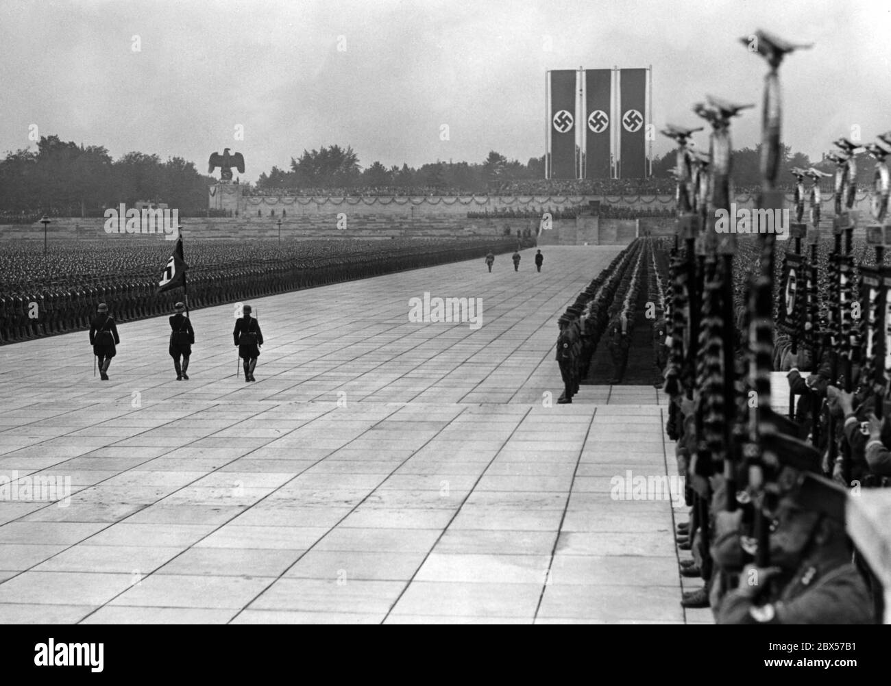 At the grand roll call of the SA, SS, NSKK and NSFK in the Luitpold Arena on the Reich Party Rally Grounds, after the laying of the wreath at the memorial, from left to right: Viktor Lutze, Adolf Hitler and Heinrich Himmler return to the rostrum. In the foreground is the Blood Flag. Stock Photo