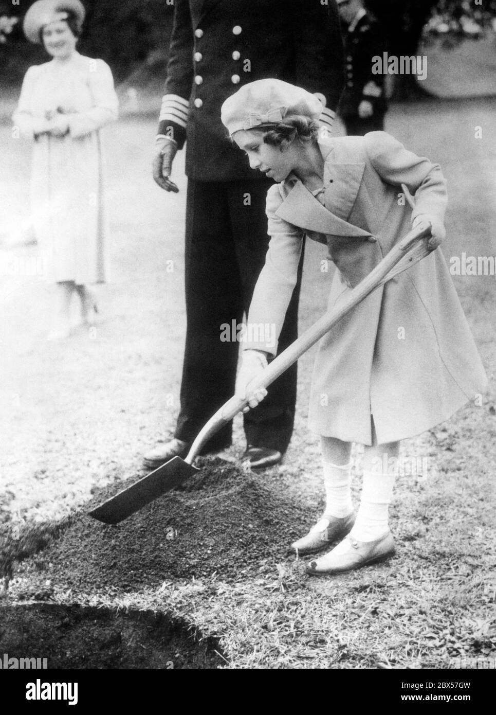 Princess Margaret digs a hole to plant a tree in front of the Royal Naval College at Dartmouth. In the background is her mother Elizabeth Bowes-Lyon. Stock Photo