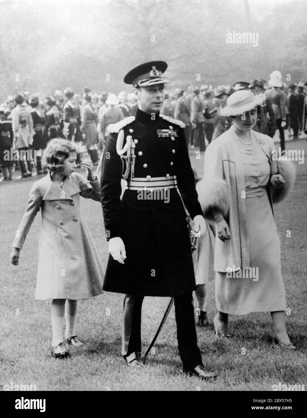 King George VI, Queen Elizabeth, Princess Elizabeth and Princess Margaret Rose ( hidden) on their way to the parade ground for the presentation of the special Coronation Medals for the Dominions and Colonial troops that will be presented at his coronation at Buckingham Palace. Over 1500 soldiers salute the Royal Family. Stock Photo