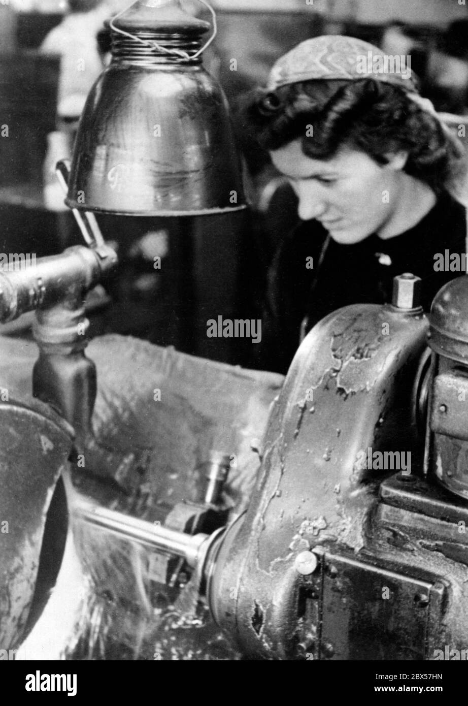 In the course of the total war, women had to increasingly replace the workers transferred to the front and do their work in the factories. Here is a female worker in a production hall of the armament industry. Stock Photo