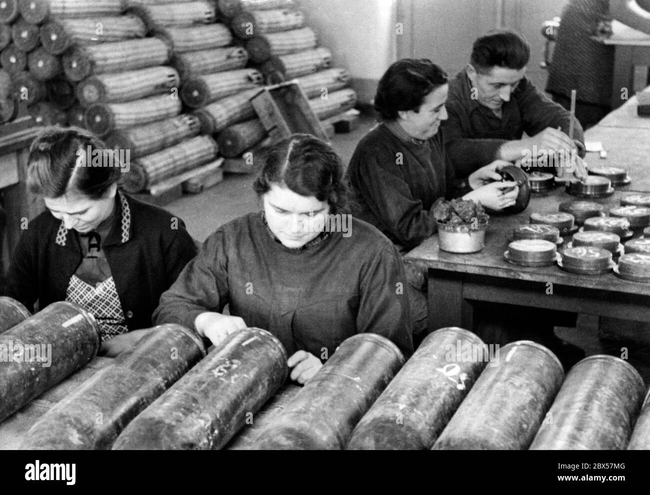 Women fill grenades with powder and then seal and compress them. Stock Photo