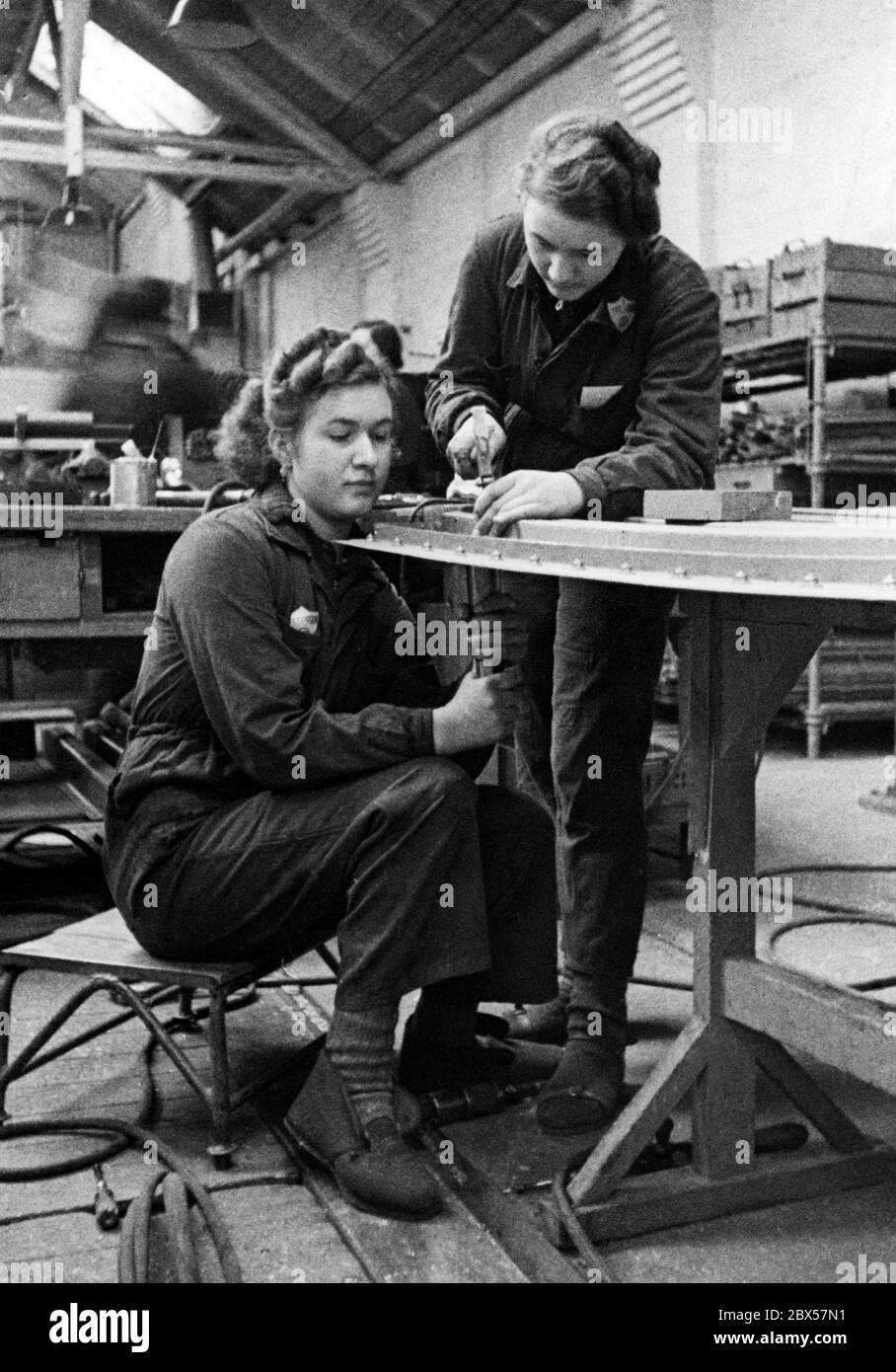 Two uniformed workers are riveting together in the aircraft manufacturing department of Heinkel Werke in Rostock. Stock Photo